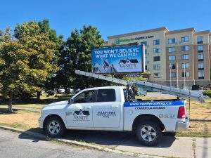 a Vanity Roofing truck in front of a Vanity Roofing billboard in Ottawa